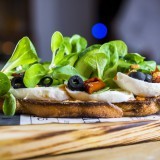 Tatine de búfala, tomate seco, aceituna negra, canónigos y pesto rosso